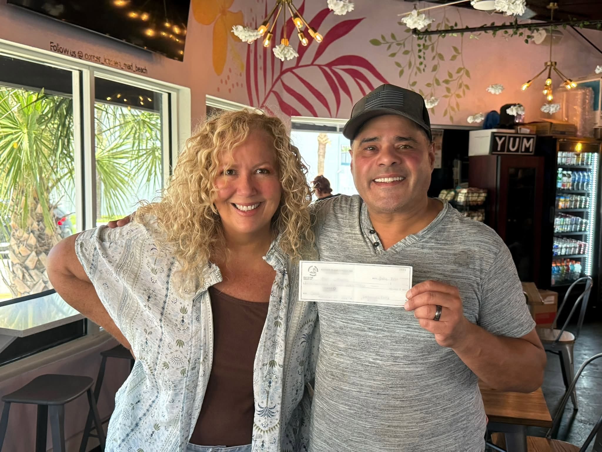 Couple holding donation check at restaurant