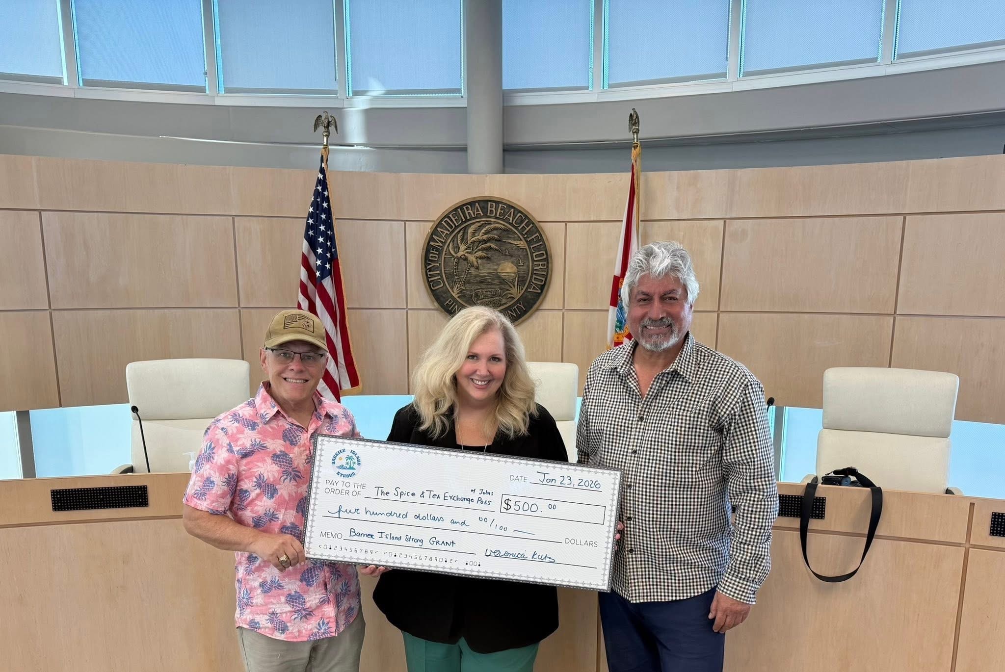 Three people holding large check at government building